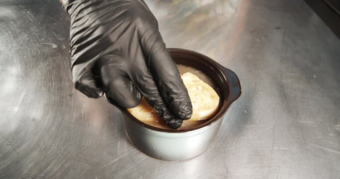Closeup of male cook hands in gloves cooking onion soup with a slice of crisp bread and cheese crust in the kitchen