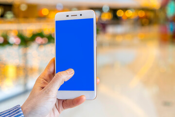 Hand holding smart phone with abstract blur in shopping mall background