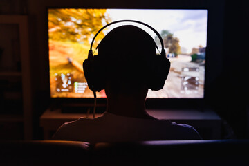 Men wearing headphones playing video games at night.