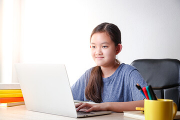 Asian girls study online from home via video call By using a notebook computer to communicate with teachers. Educational concept, social distancing to reduce the spread of coronavirus (COVID-19)