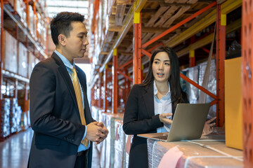 Manager In Warehouse checking product in a large warehouse,Two Business People working at Warehouse.