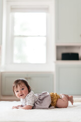 Fototapeta premium Smiling baby girl crawling on the floor