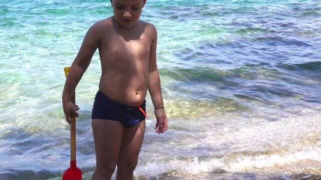 Caucasian toddler boy playing at beach of Sesi, Atiica, Greece, on a shiny summer day 120fps