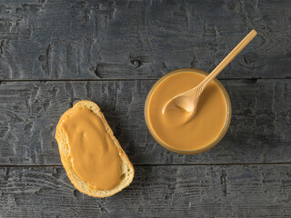 A bowl of peanut butter and bread on a black wooden table.