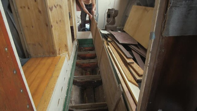 Young man lifting floorboard to reveal bilge of wooden boat
