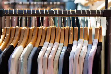 Multi-colored women's sweaters hang on wooden hangers close-up.