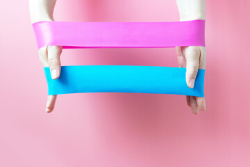 The girl holds two fitness gums, Espander, on pink background, view from above