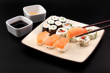Raw fish dish, healthy food and authentic Japanese cuisine concept with photograph of sushi mixed platter with various rolls isolated on black background with clipping path cutout