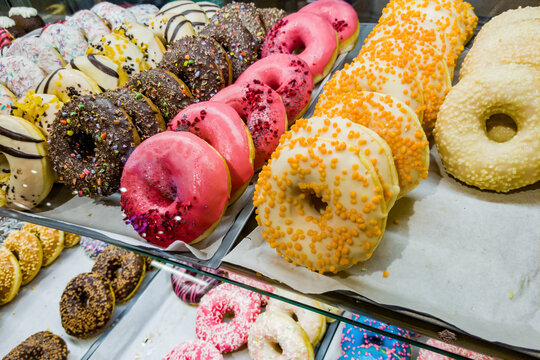 Multi-colored Donuts Lie In A Row On A Shop Window.