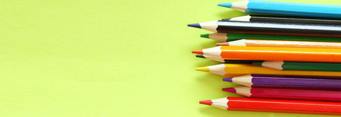 Colored pencils on a yellow background. Lots of different colored pencils. Colored pencil. Pencils are sharp. Pencils are on the right. Close-up. Copy space. Background. Banner
