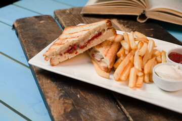 Club sandwiches served with fried potatoes in white plate