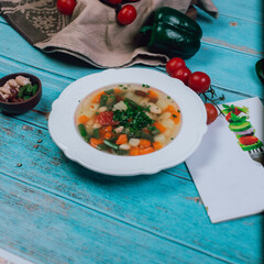 Vegetable soup served with minced herbs in white plate