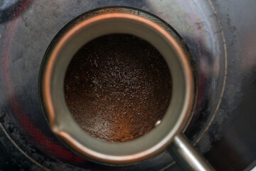 coffee turk with ground coffee on an electric stove, top view