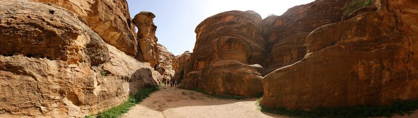Entrance of the Little Petra canyon of Jordan featuring the famous red sandstone rock formations int the arid landscape. 
