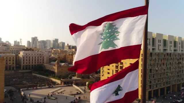 Beirut, Lebanon 2019: sunset turn around close up drone shot with Lebanese flag in foreground, mosque, church and sun flaring in the background during the Lebanese revolution