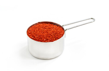 Korean dried red chilli powder in measuring stainless steel cups, isolated on white background. Korean cayenne for Kimchi cooking.