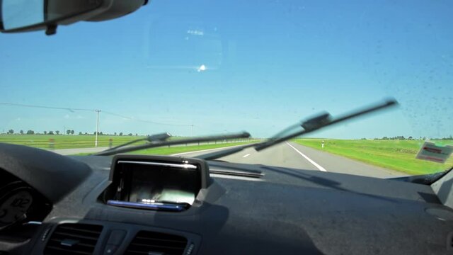 Car wipers clean windshield of dirt and insects while driving, inside view