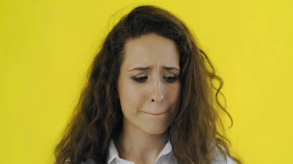 Sad beautiful woman cries at camera on yellow background