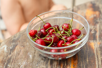 A plate of sweet cherry in front of a child, outdoor in garden