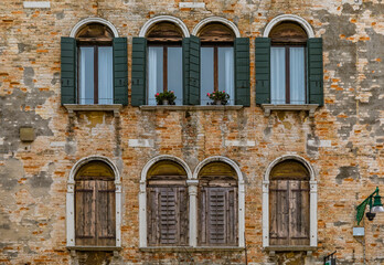 Fototapeta na wymiar Facade of an old building with shutters and ornate windows in Venice Italy