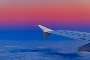Colorful fluffy clouds and airplane wing from an airplane at sunset