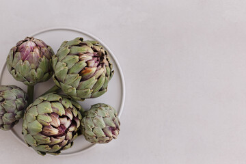Obraz premium Minimalistic image of artichokes in a white plate on a light gra