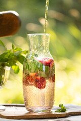 Lemonade. Homemade lemonade in nature. Beautiful drink in the forest. Nice cold drink. Carafe with cold compote. Lemonade with strawberries and basil. Drink with berries and mint.