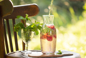 Lemonade. Homemade lemonade in nature. Beautiful drink in the forest. Nice cold drink. Carafe with cold compote. Lemonade with strawberries and basil. Drink with berries and mint.