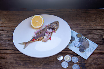 fried fish on a plate with stacked coin, Economic crisis