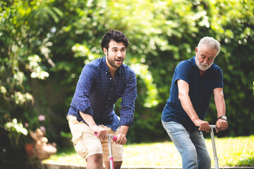 An adult hipster son and senior father living at home, playing scooter with family