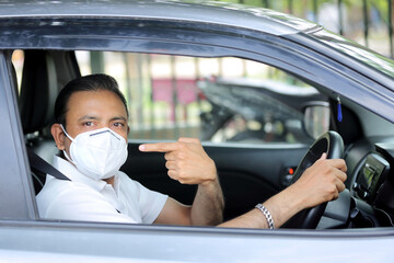 Man driving car with mask on. Protection against covid-19. Drive safely. 