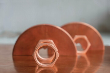 Hexagonal copper nut on a background of copper tools.  Reflection of tools in a copper plate. Copy space. 