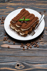 Classic tiramisu dessert on ceramic plate on wooden background