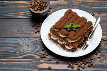 Classic tiramisu dessert on ceramic plate on wooden background