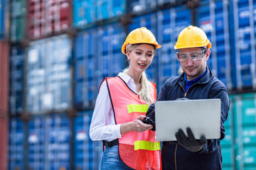 Logistic worker man and woman working team with online wireless laptop control loading containers at port cargo to trucks for export and import goods
