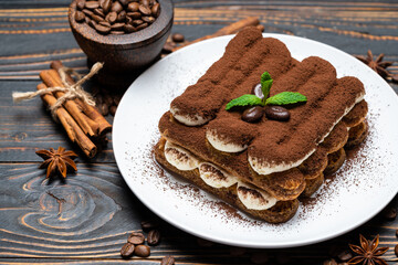 Classic tiramisu dessert on ceramic plate on wooden background