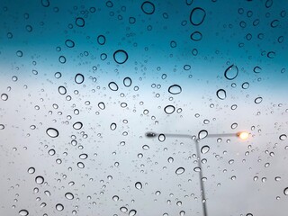 rain drops on the car sunroof with lamp pole on the street backdrop