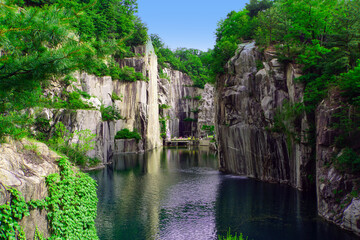 Fototapeta na wymiar Landscape with stone mountains and emerald man-made lake. Granite valley. Pocheon Art valley, South Korea