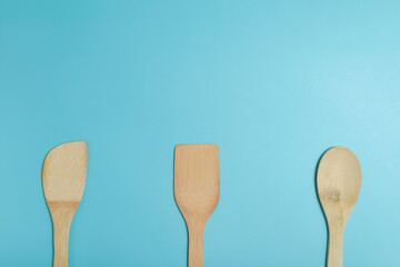 Three wooden spatulas on light blue surface.