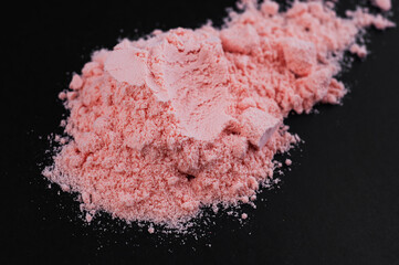 Pink protein powder with strawberry flavor on a black background. Sports supplements and nutrition...