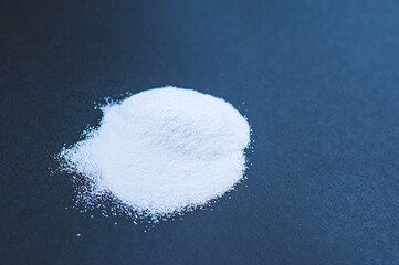 White powder of tasteless creatine on a black background. Sports supplements and nutrition for...