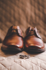 cuff links and shoes on a brown background