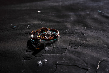 gold and silver rings lie on a glass surface in water