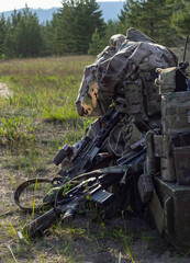 Rifles, camouflage backpack and uniform, ammunition, radio, box on military range, army weapon of active game airsoft