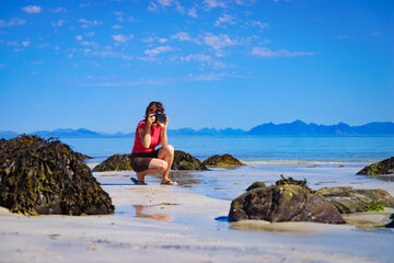 Fototapeta na wymiar Woman take photo on beach, Lofoten Norway