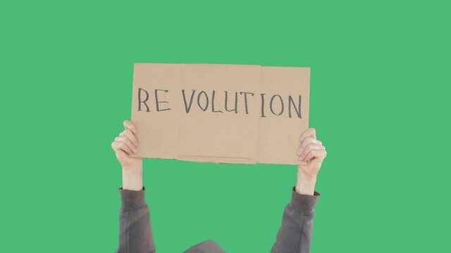 Protester hands holding cardboard banner with revolution inscription sign on green chromakey background. Unrecognizable man showing revolution sign on cardboard