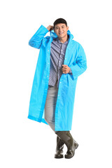 Young Asian man in raincoat on white background