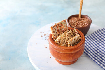 Bowl with cereal cookies and flax seeds on color background