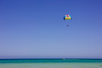 Parachute in the sky above the beach and the sea