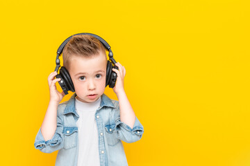 Portrait of little boy wearing headphones over isolated yellow background